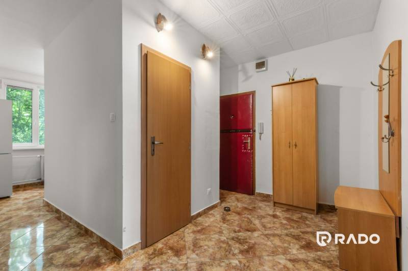 A hallway in a 3-room apartment with a coat rack, a wardrobe, and dark tiles.