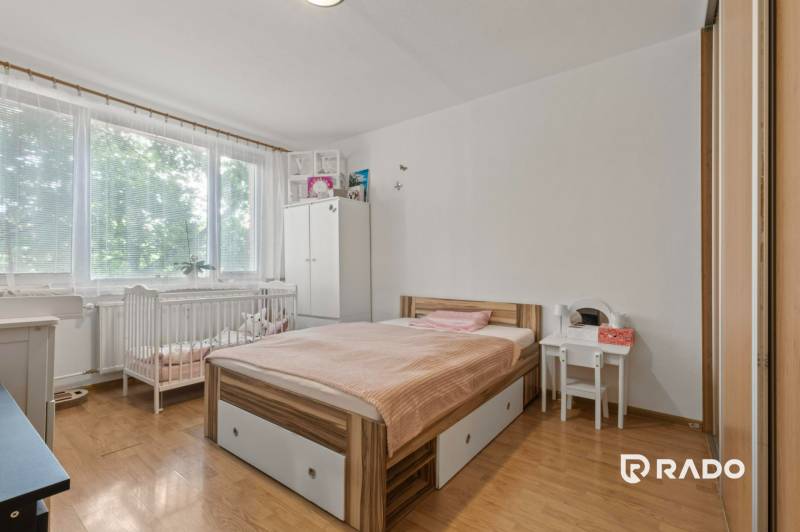 Bedroom with a crib, bed, and wooden floor in a 3-room apartment.