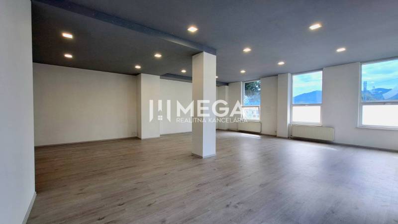 A spacious office interior with wooden flooring and ceiling lighting.