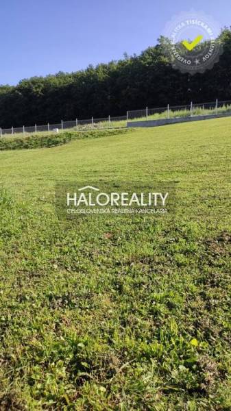 A green grassy plot in Horná Ves suitable for living, fenced, with a forest in the background.