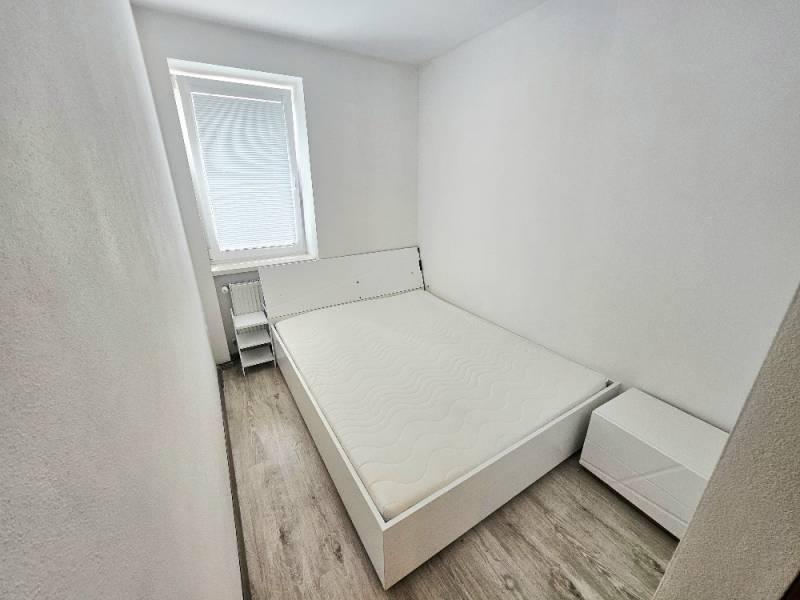 Bedroom with a bed and a nightstand in a 2-room apartment.