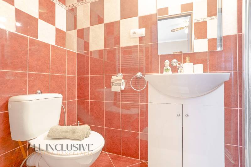 Bathrooms in hotels and guesthouses with red tiles, a sink, a toilet, and a mirror.