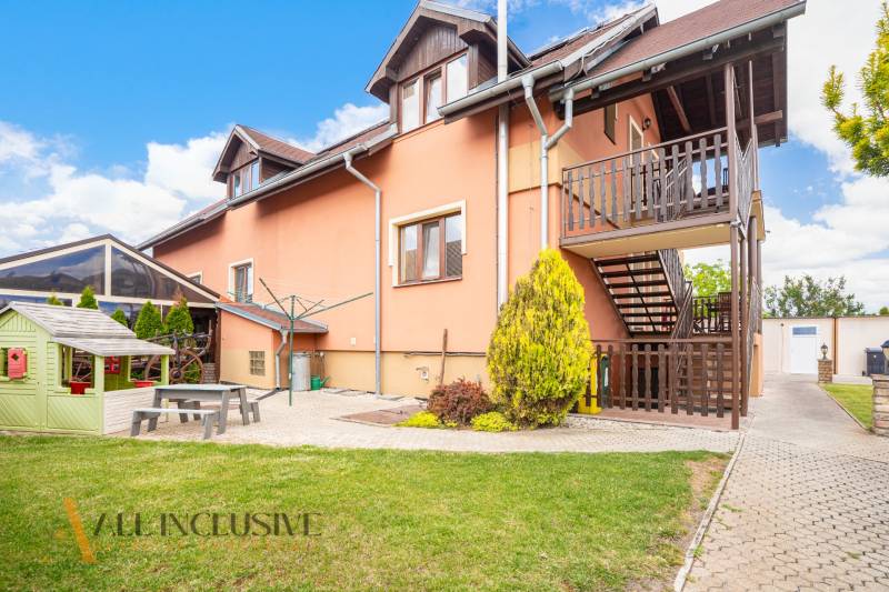 Exterior of the building with wooden terraces, garden, and playground in Veľký Meder, hotels and guesthouses.