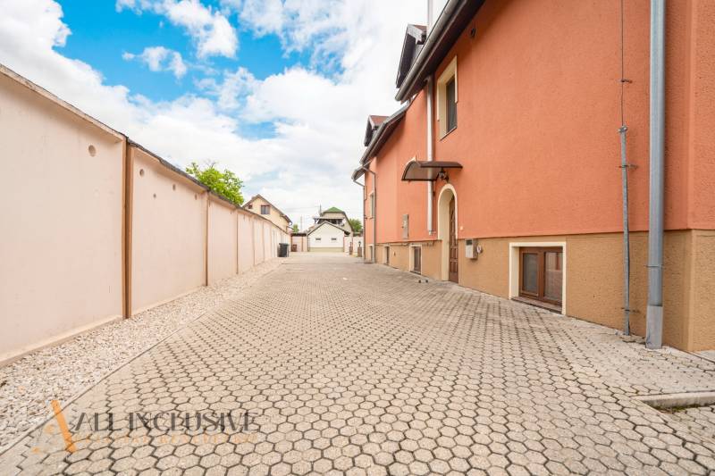 A flat path lined with an orange building in the premises of hotels and guesthouses in Veľký Meder.