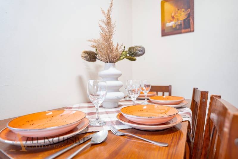 Table with place settings, ceramic plates, glasses, and decorations in hotels and guesthouses.