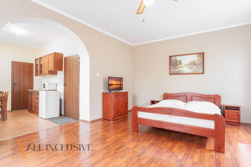 A room with a wooden bed, kitchenette, and television in hotels and guesthouses.