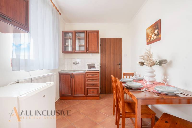 Kitchen in hotels and guesthouses with wooden cabinets, a table, and decoration on the table.
