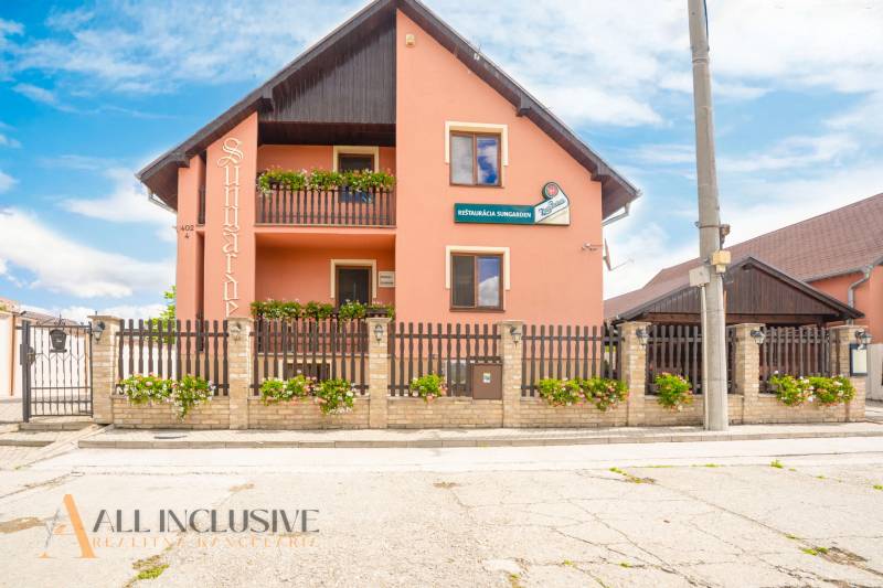 Guesthouse with a wooden fence and floral decorations in the town of Veľký Meder.