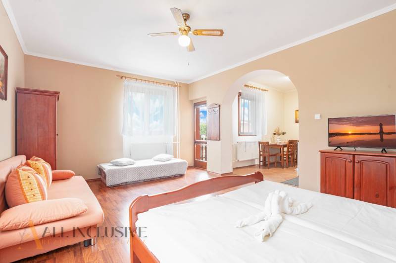 A room in a hotel and guesthouse with a bed, sofa, and dining seating.