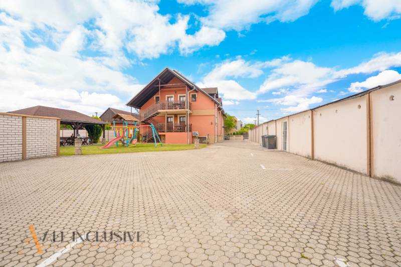 Exterior of hotels and guesthouses in Veľký Meder with a children's playground and parking lot.