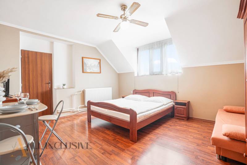 Hotel rooms and guesthouses with wooden beds, white bed linens, and a table with dishes.