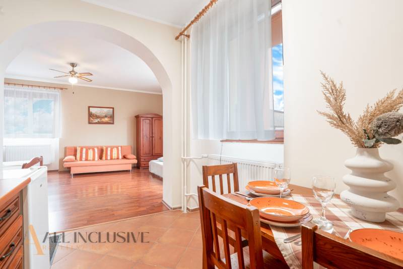Dining and living area in a guesthouse with wooden furniture and decorations.