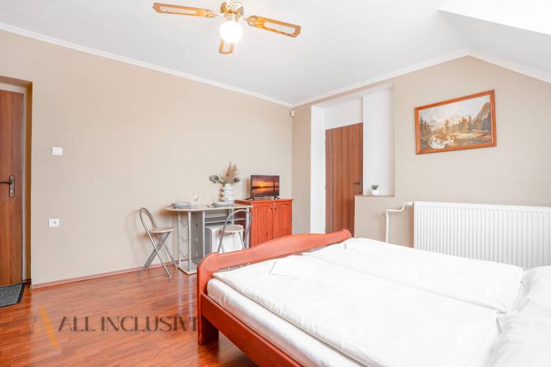A bright hotel room with a double bed, decorations, and a dining area.