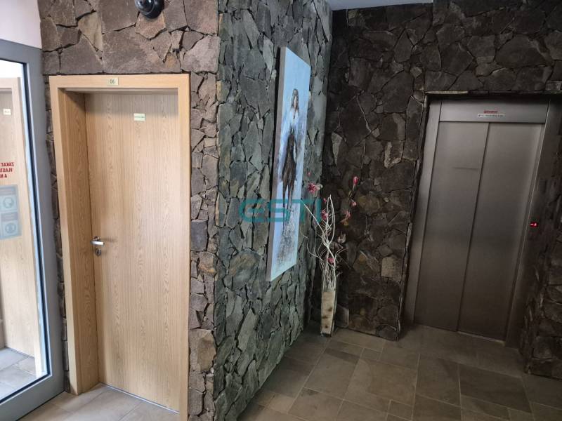 Entrance area with an elevator and wooden doors in a 1-room apartment.