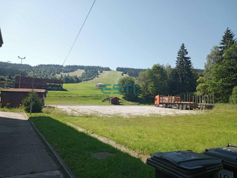 Landscape in Makov with a truck, grassy slope, and trees on the horizon.