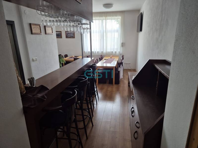 Bar counter and dining table in a studio apartment with wooden flooring.
