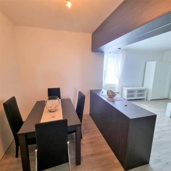 Dining area in a 2-room apartment with a black table and chairs, bright interior.