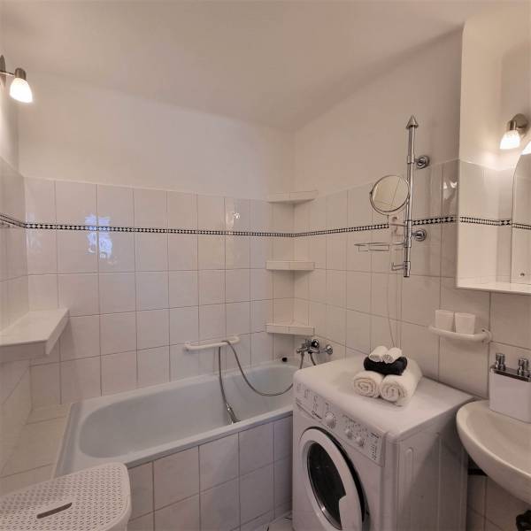 Bathroom with a bathtub, washing machine, and sink in a 2-room apartment.