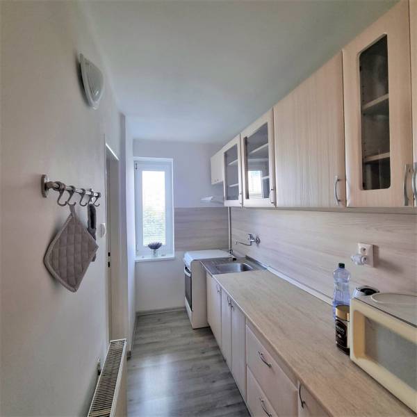 A kitchen in a 2-room apartment with wooden cabinets and appliances.