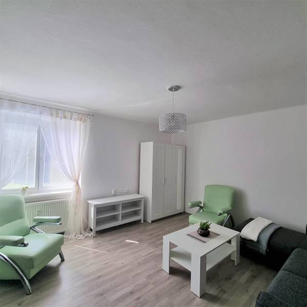 Living room in a two-room apartment with furniture, green armchairs, and a table.