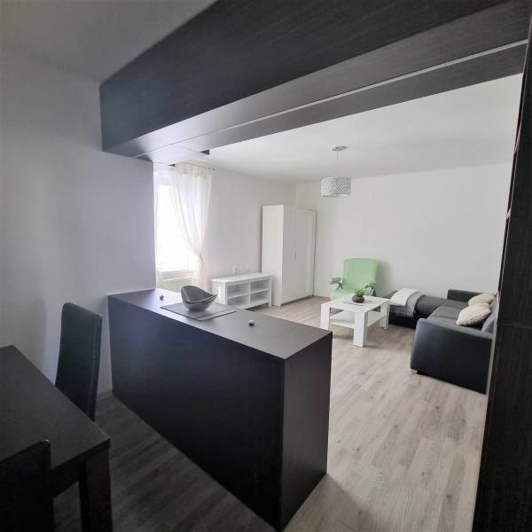 Interior of a 2-room apartment with a sofa, table, and dining area.