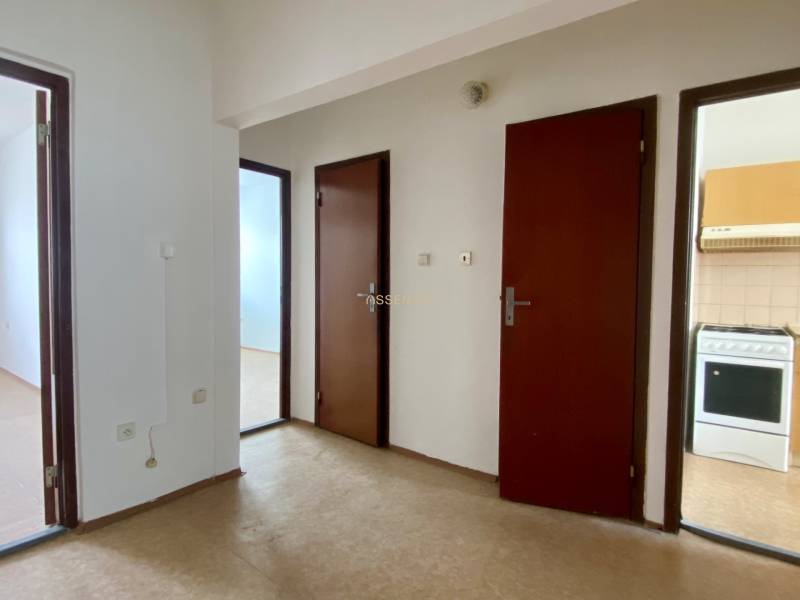 A hallway with three brown doors in a 3-room apartment, entrance to the kitchen.