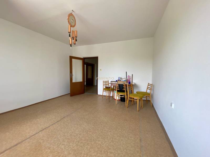 A spacious room with a dining table in a 3-room apartment, wooden chairs and a chandelier.