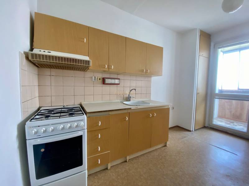 A kitchen in a 3-room apartment with a gas stove and light-colored furniture.