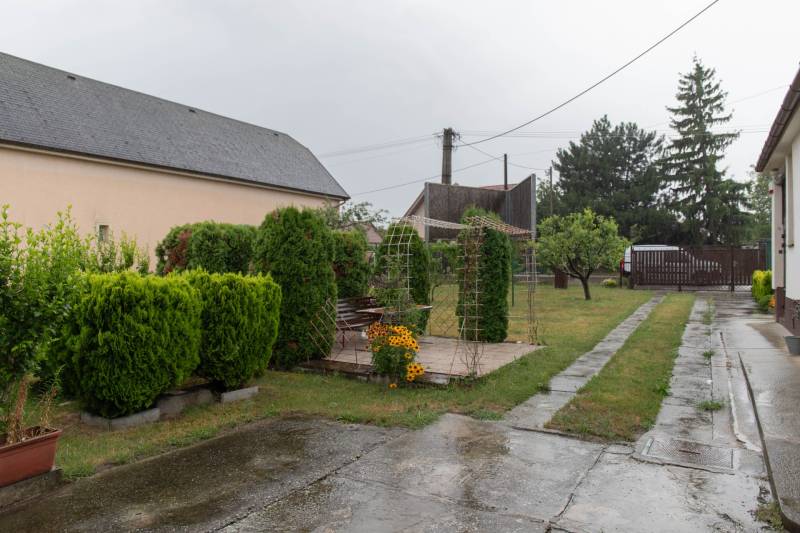 The garden of a family house in Rovinka with a walkway, greenery, and a gazebo.