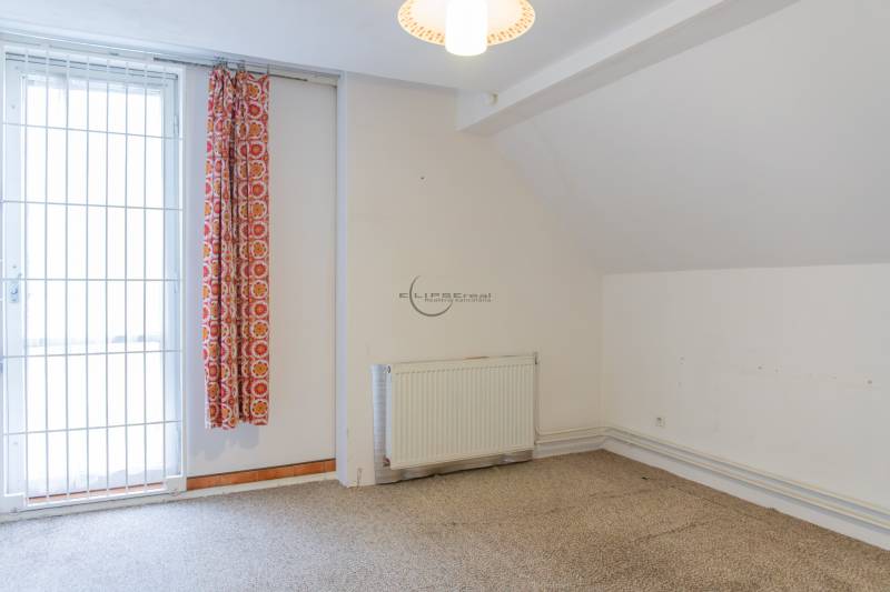 Interior of a family house with a curtain, radiator, and white wall.