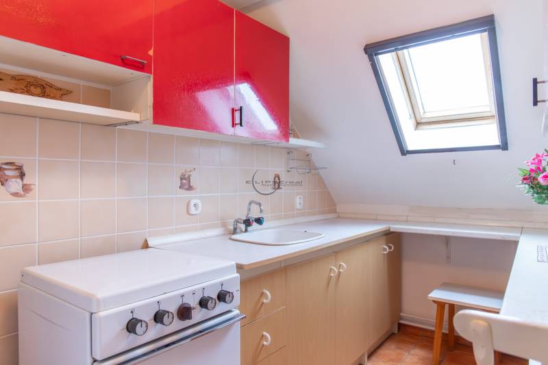A kitchen with red cabinets, a skylight, and a stove in a family house.