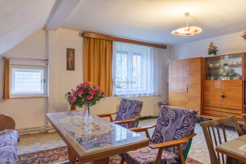 Living room in a family house with flowers, furniture, and artwork on the wall.