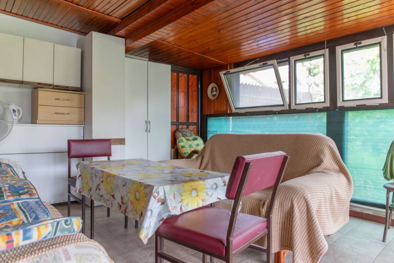 Interior of a family house with a dining table, chairs, and a sofa, wooden ceiling.
