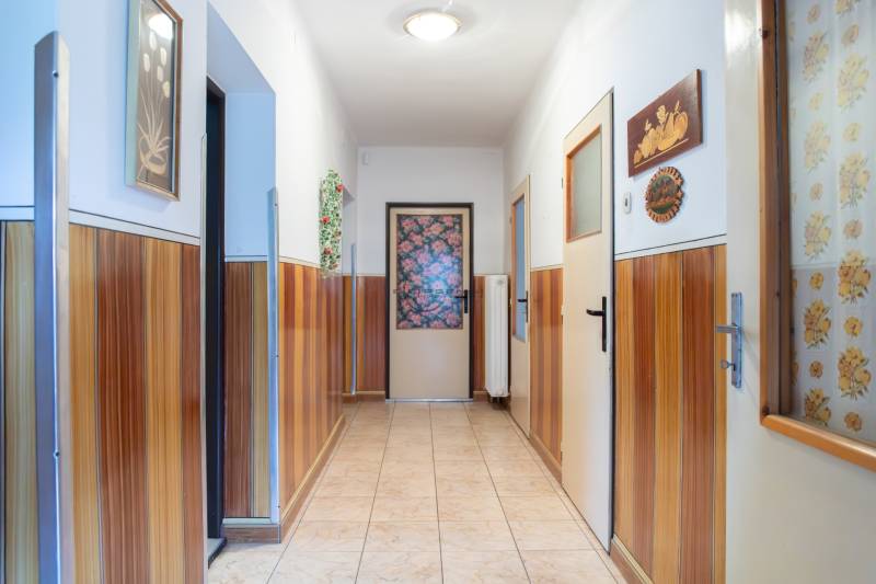 A hallway in a family house with wooden paneling and decorative pictures on the walls.