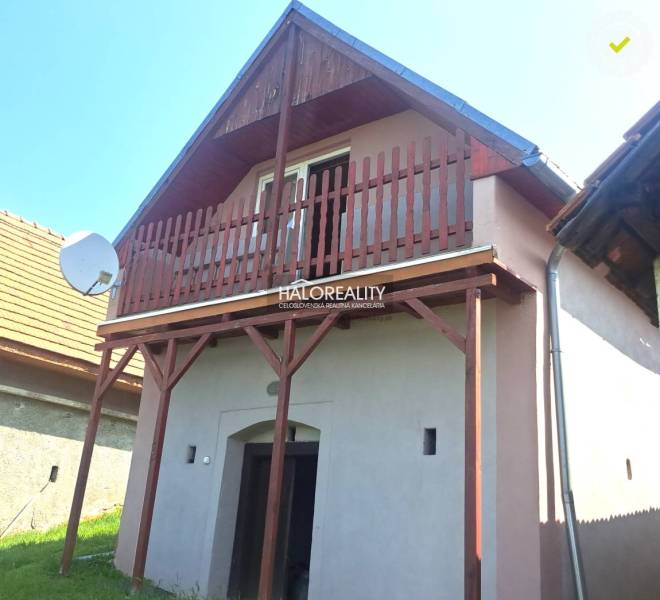A cottage in Hontianske Trsťany with a wooden balcony and a satellite dish on the roof.