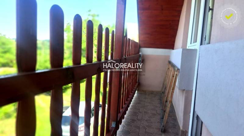 A wooden balcony with a railing on a cottage in Hontianske Trsťany, overlooking the garden.