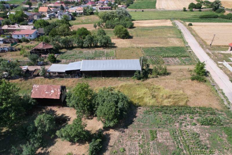 Rural house construction in Štrkovec with agricultural land, trees, and a road in the vicinity.