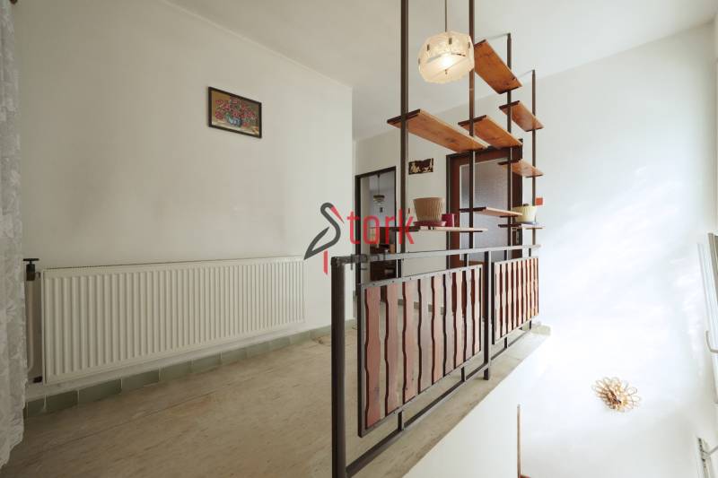 A hallway in a family house with wooden shelves and railing.