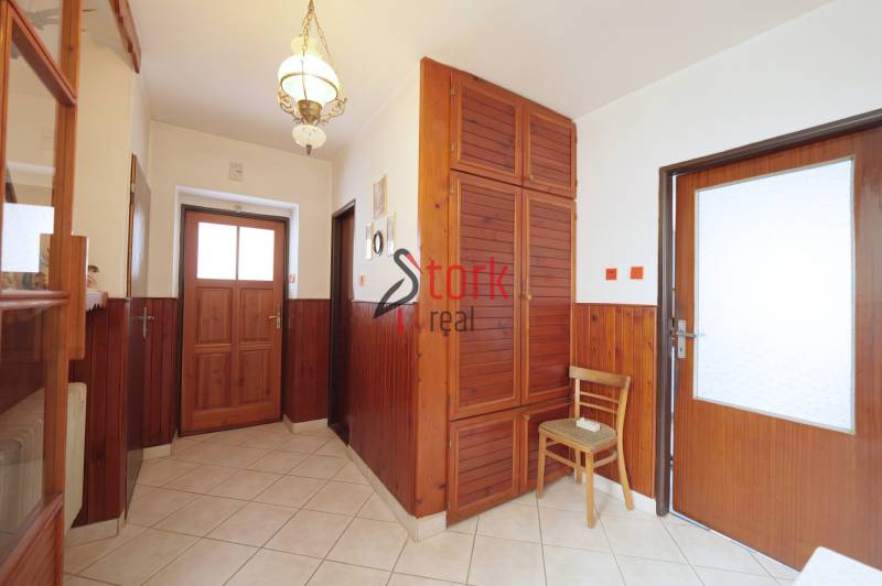 A hallway in a family house with wooden paneling, a cabinet, and tiles.