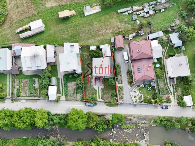 An aerial view of a row of family houses in Dolná Mariková with a river in the foreground.