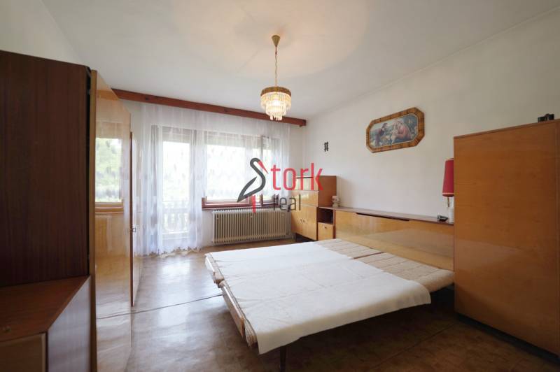 Bedroom in a family house with wooden furniture and a chandelier.