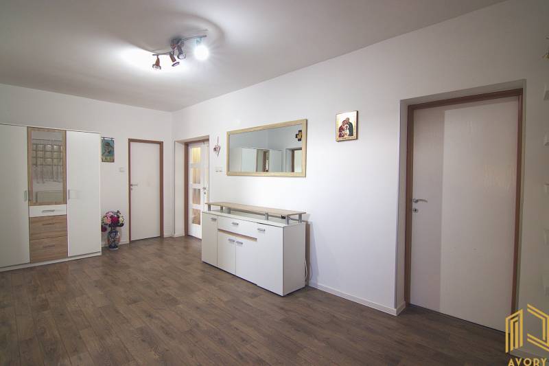 Interior of a family house with white furniture, wooden decor flooring, and a large mirror.