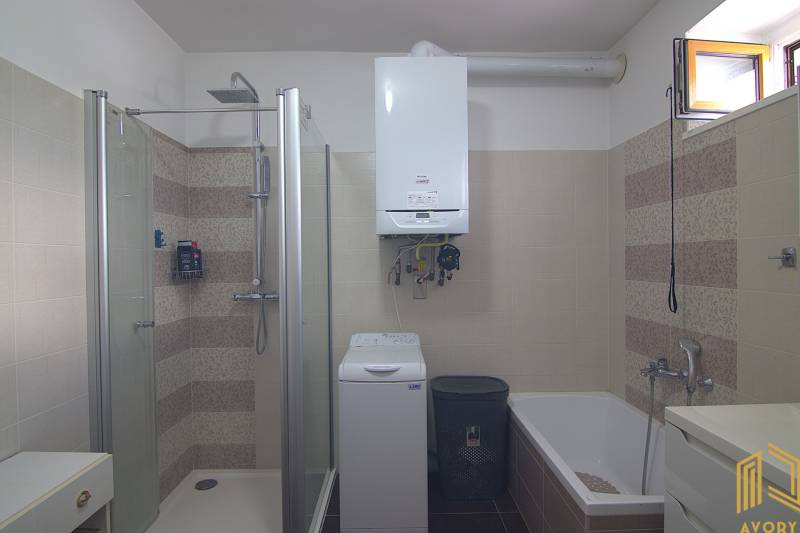 Bathroom with a bathtub, shower, washing machine, and gas boiler in a family house.