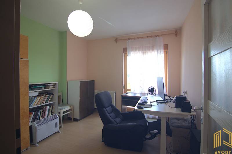 A study in a family house with a computer, a bookshelf, and a comfortable armchair.