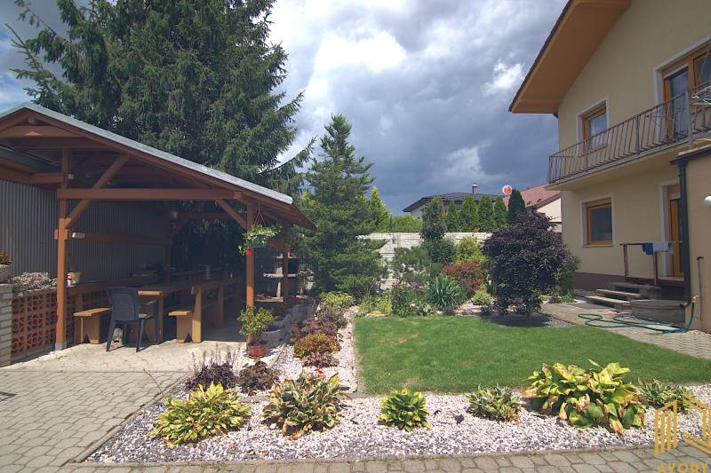 The garden of a family house on Športová Street in Brodské, with a gazebo and flower beds.