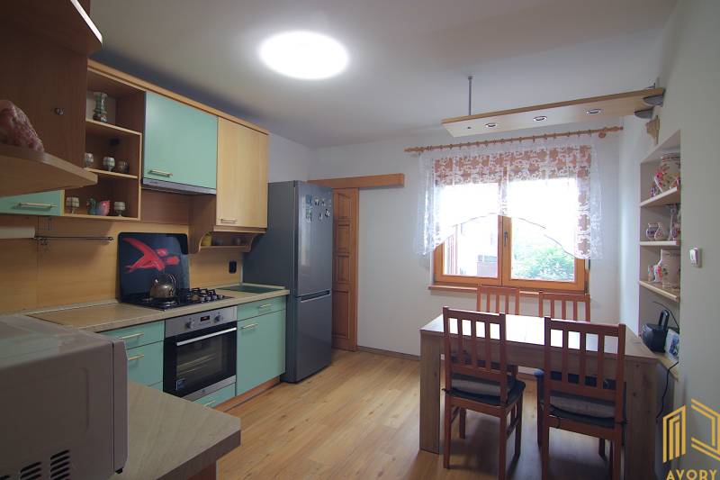 A kitchen in a family house with a kitchen unit, table, and chairs.