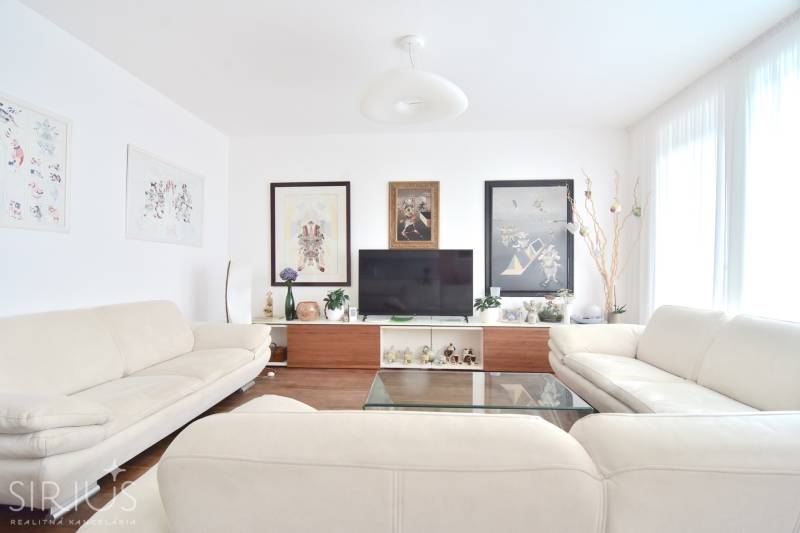 Bright living room with paintings, sofas, and a television in a 4-room apartment.