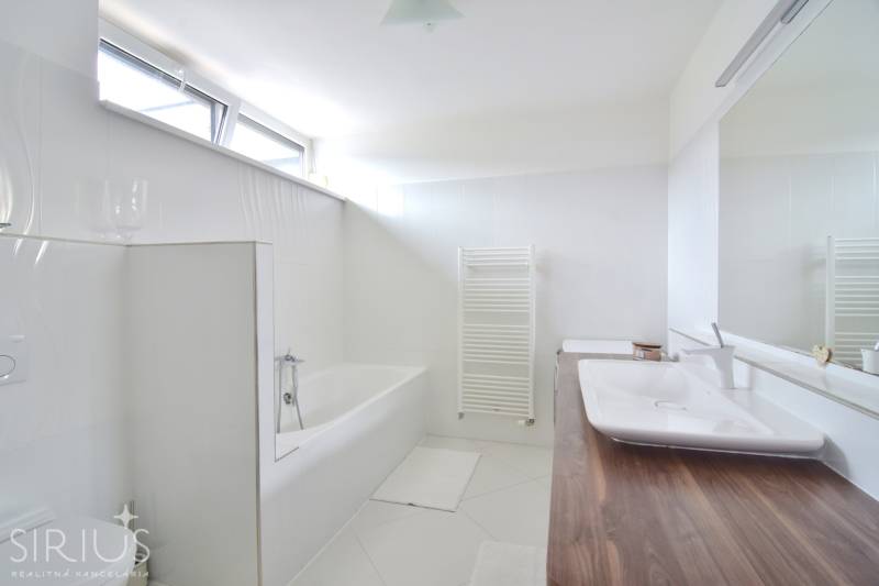 Bathroom in a 4-room apartment with a bathtub, sink, large mirror, and window.
