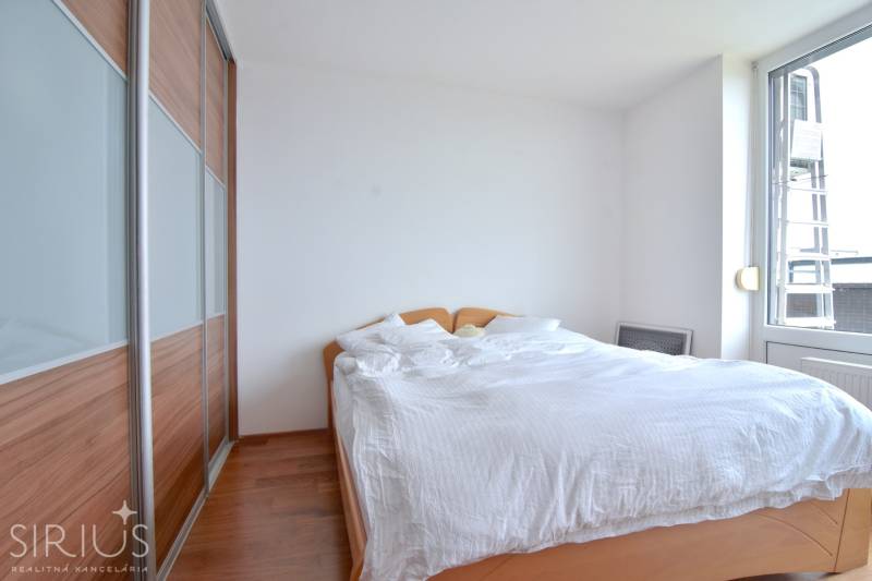 Bedroom in a 4-room apartment with a bed, built-in wardrobe, and a large window.