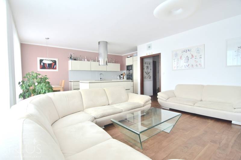 A spacious living room with a cream sofa and a kitchen in a 4-room apartment.